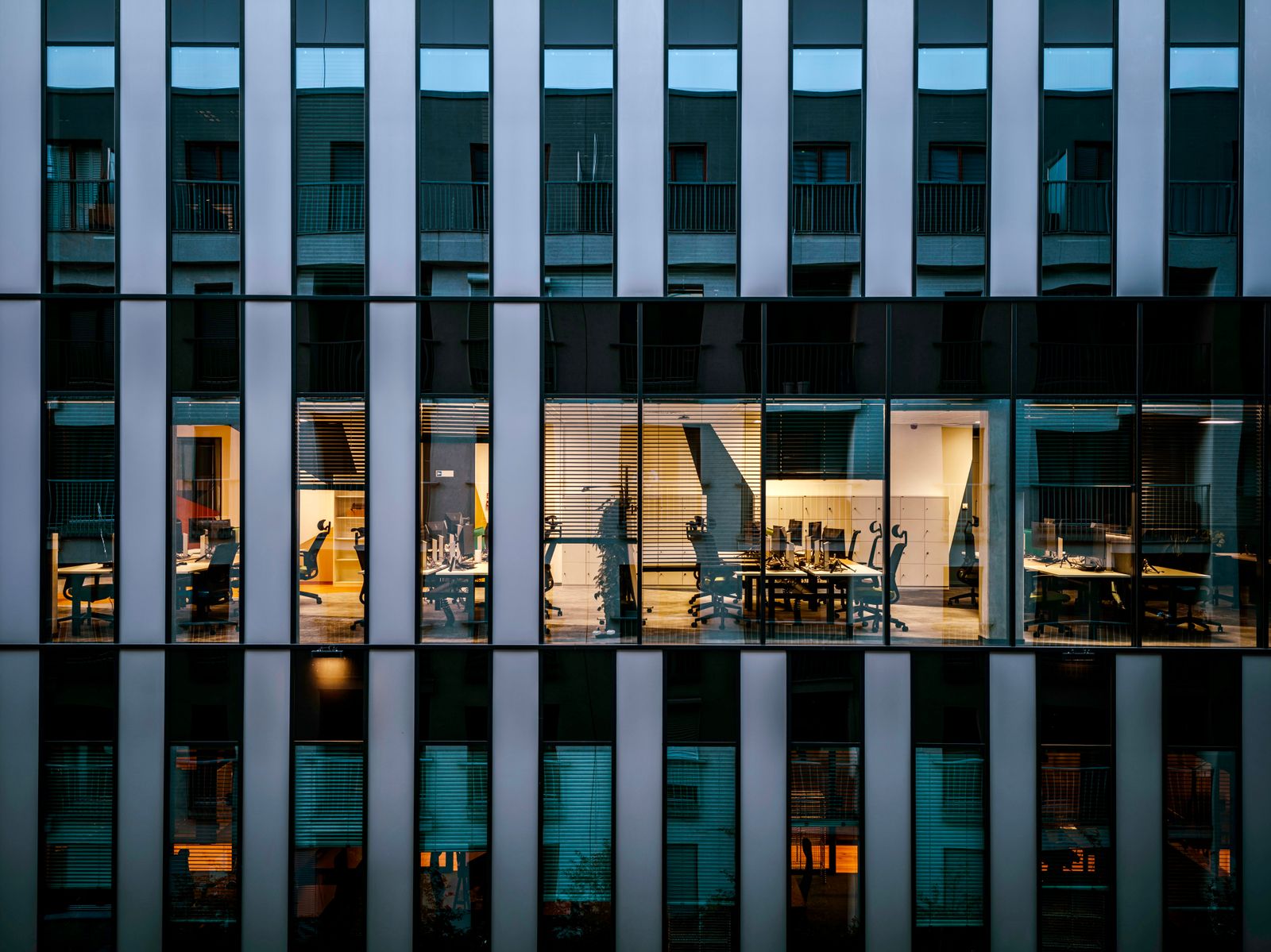 Lit offices behind a glass building facade